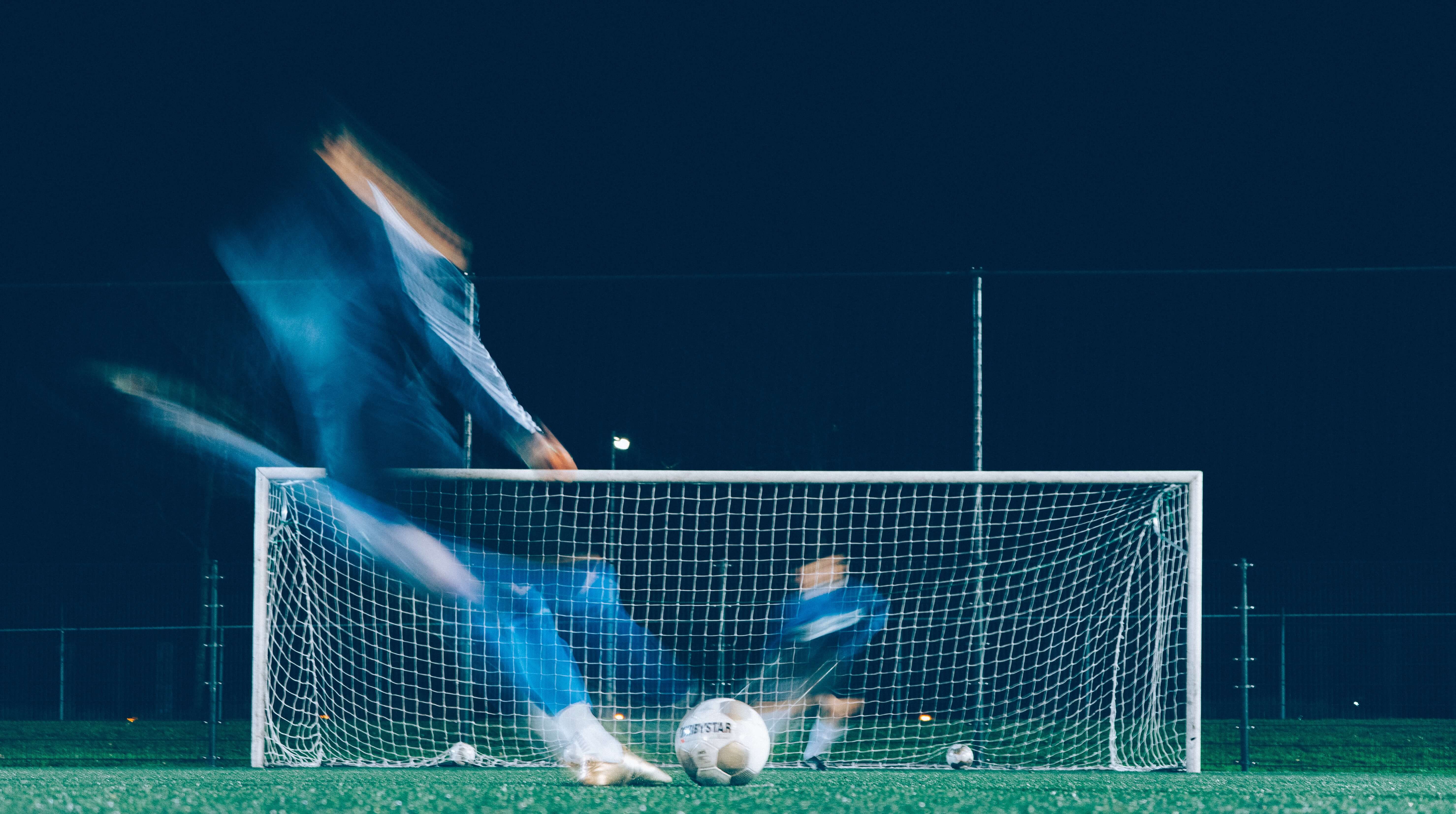 soccer player kicking a ball into the goal during a pickup session at your local field